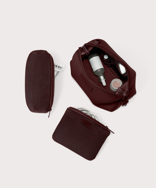 Dagne Dover Large Hunter Toiletry Bag in a deep brown with purple undertones unzipped and seen from above with the removable air mesh pouch alongside it.