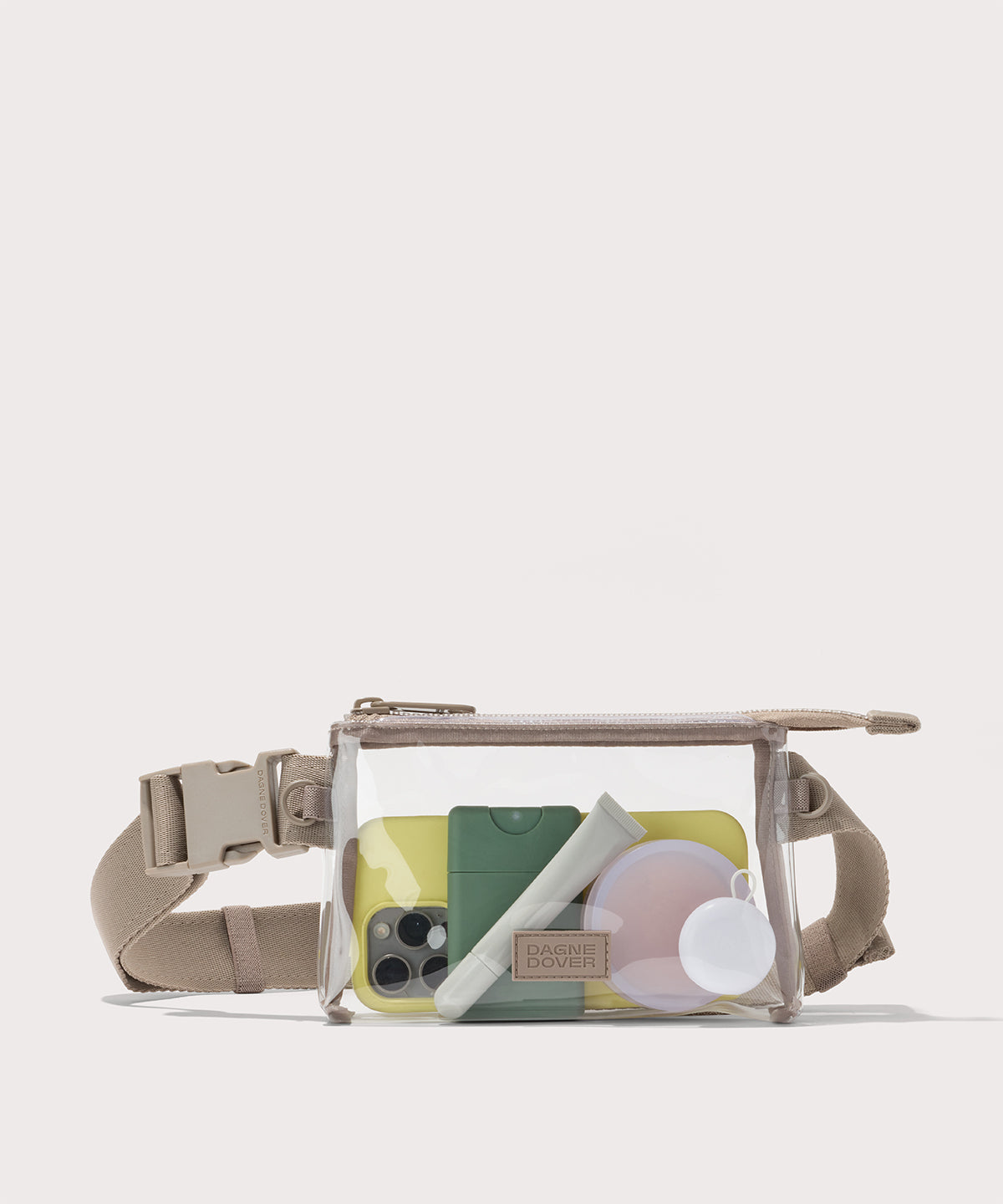 Clear crossbody bag with beige strap on a white background with phone and accessories Stadium compliant.
