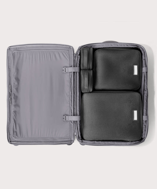 Top down of Sydney checked rolling luggage 28.5” in light grey with interior divider zipped and packing cubes packed into the right side.